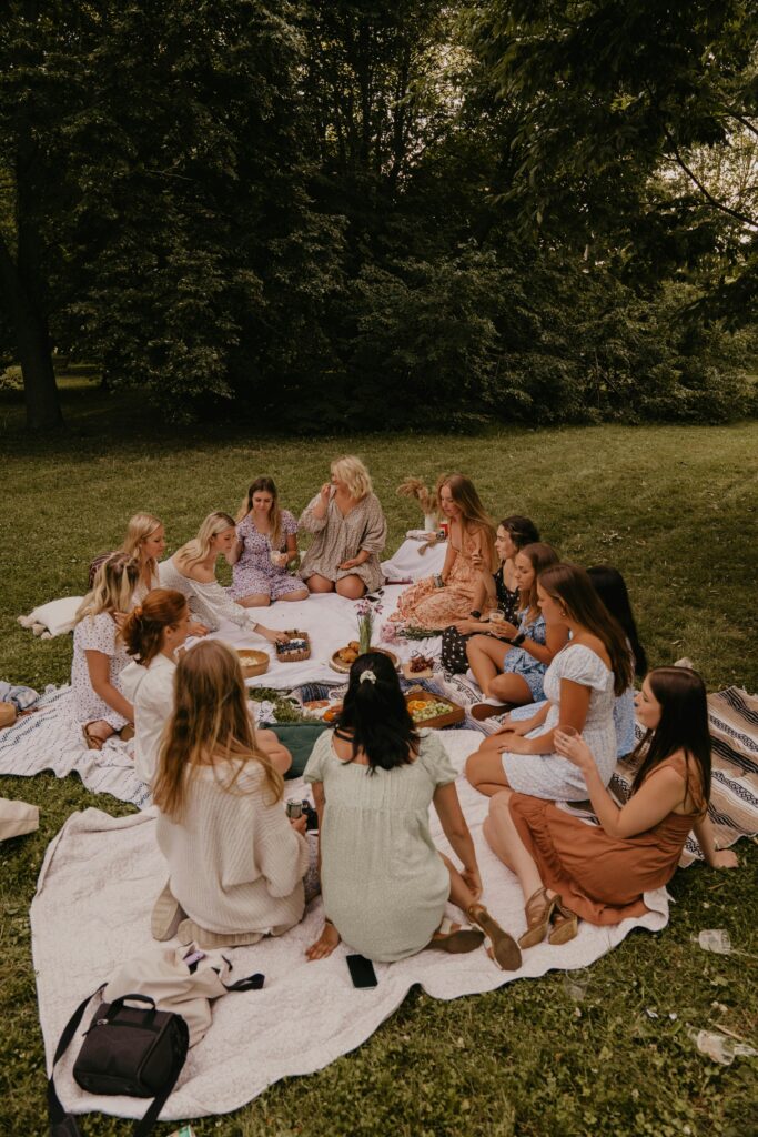Group of women having a picnic in a park, enjoying food and leisure on a sunny day.