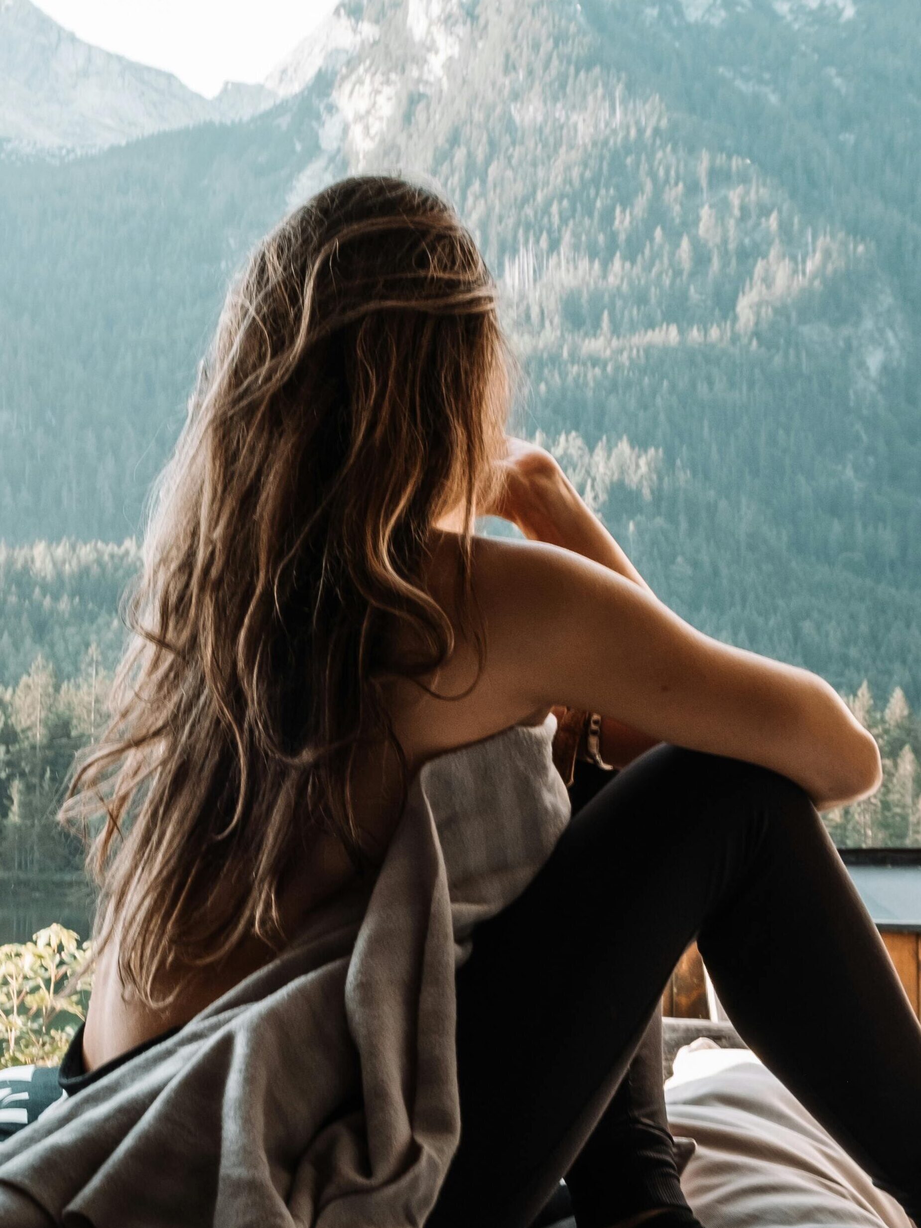 A woman enjoying a peaceful moment inside a campervan with a stunning mountain view, embracing the van life and nature.