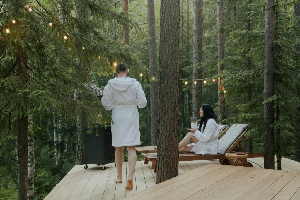 A couple enjoying a peaceful retreat in the forest, relaxing in bathrobes amidst nature on a sunny day.